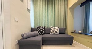 A modern living room with a sectional sofa, a window with a view, and a curtain. - Viridis | Penthouse Pignasecca – Design Suite (Naples)