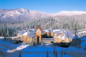 Ein großes Chalet mit mehreren Gebäuden, umgeben von schneebedeckten Bäumen und Bergen.