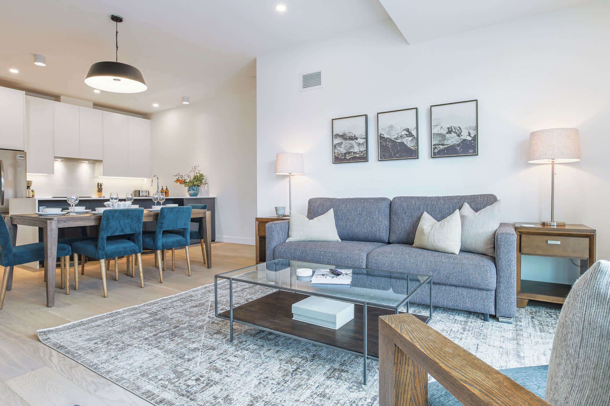 A modern living room with a sofa, coffee table, and dining area.