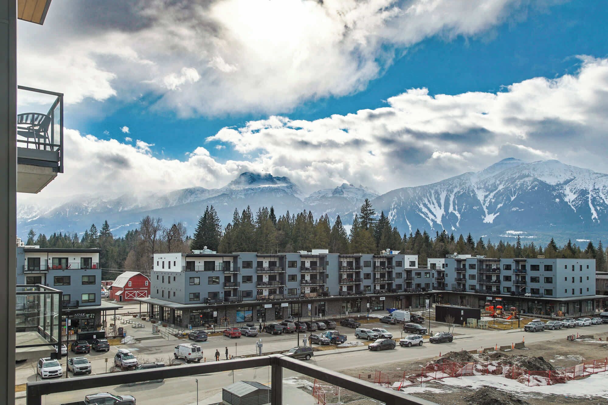 A view of a hotel with multiple buildings, a parking lot, and a mountain range in the background.
