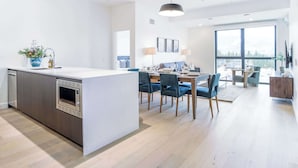 Une cuisine moderne dotée d’un îlot central, d’un coin repas avec des chaises et d’une grande fenêtre.