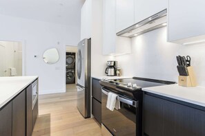A modern kitchen with a built-in oven, a coffee maker, and a knife block. - Adventure Living - Cozy 2 Bedroom Condo (Revelstoke)