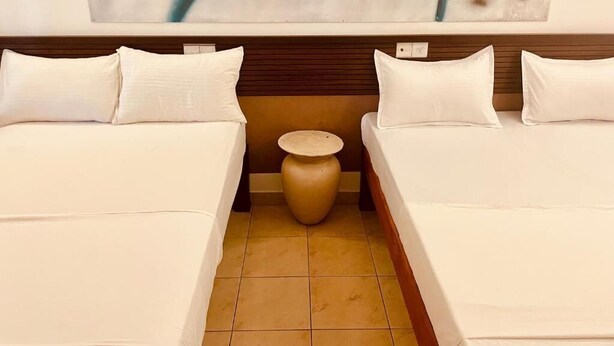 Ein Hotelzimmer mit zwei Betten, einem kleinen runden Tisch und einem großen abstrakten Gemälde an der Wand.