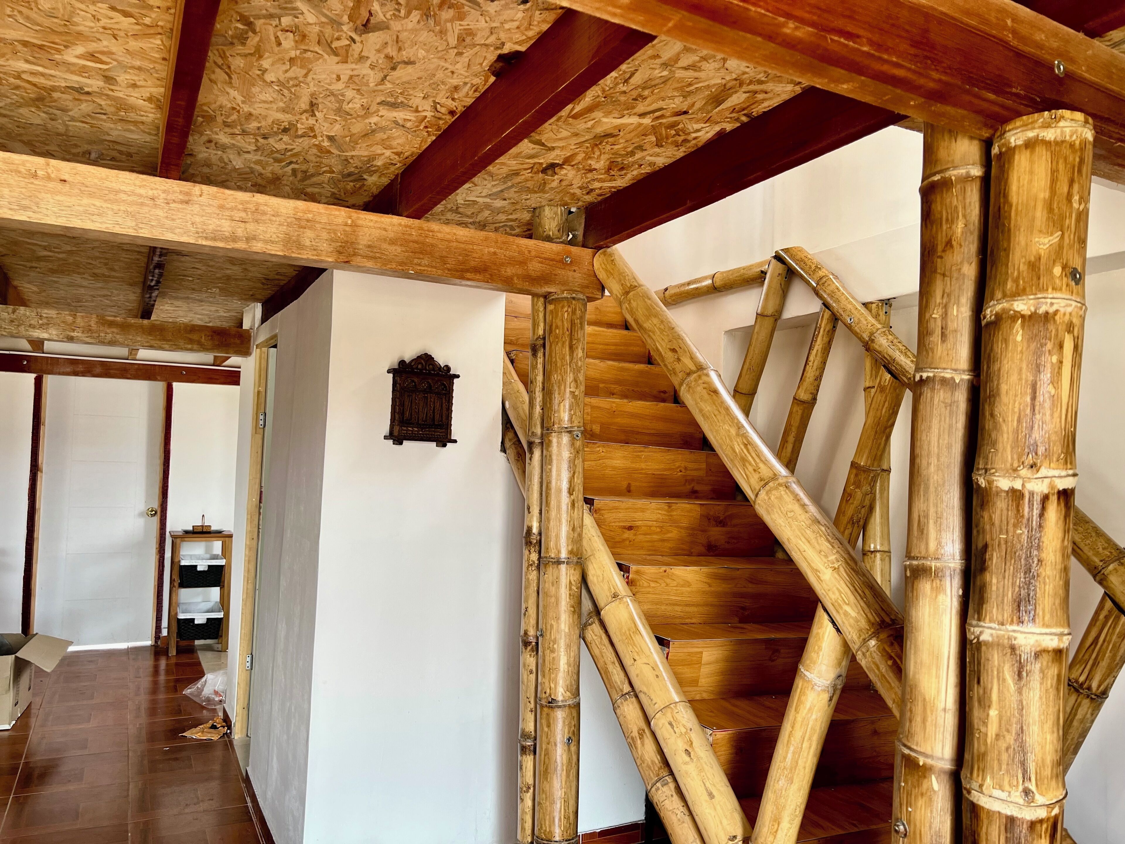 A wooden staircase with bamboo railings and a white wall with a small decorative item.