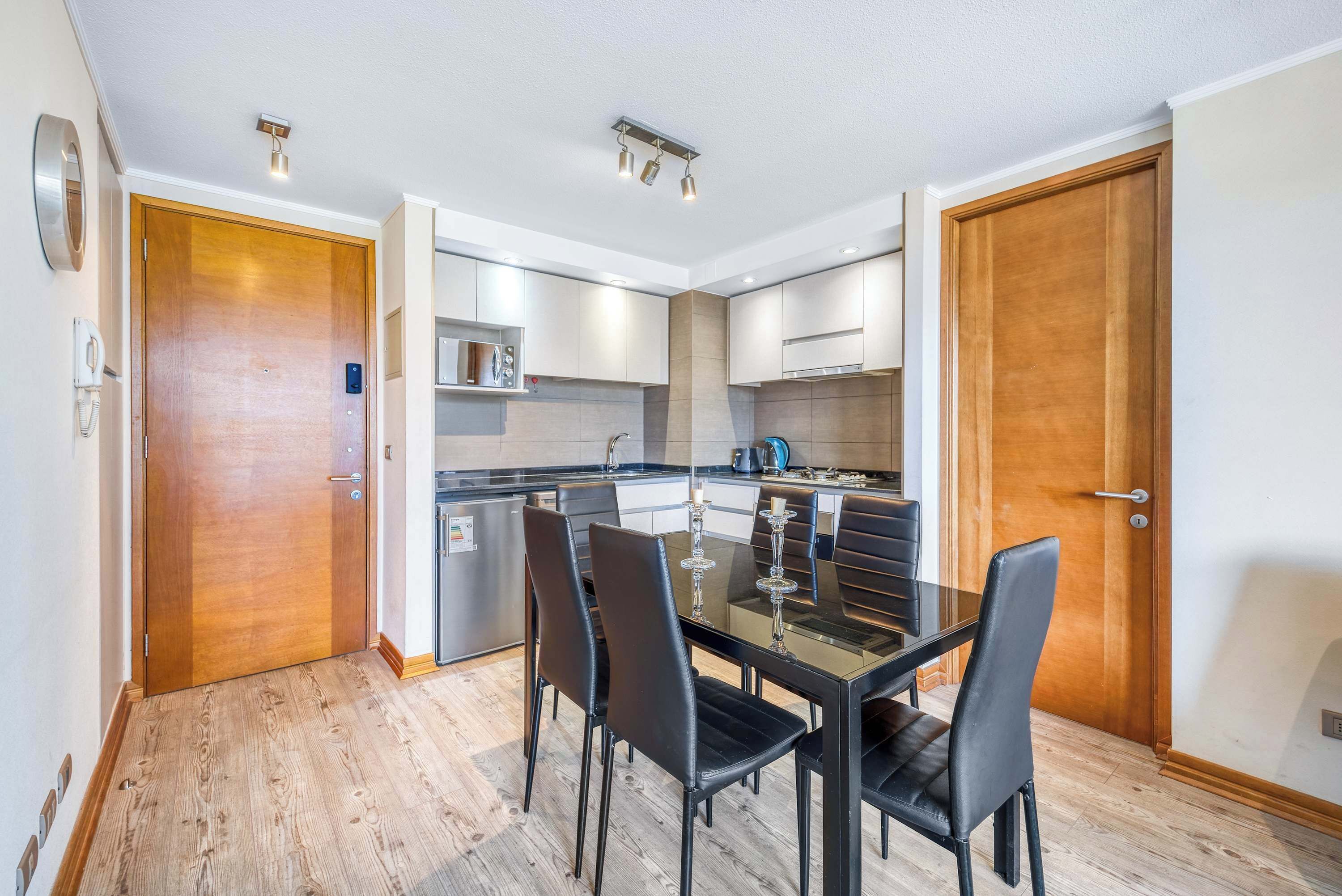 A modern kitchen with a dining area, wooden flooring, and built-in appliances.