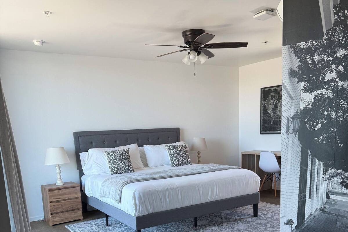 A bedroom with a bed, nightstands, a ceiling fan, and a rug.