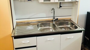 A compact kitchen with a double sink, white cabinets, and a small countertop. - Cozy studio apartment in the center, steps away from the cable car 🚡 (La Paz)