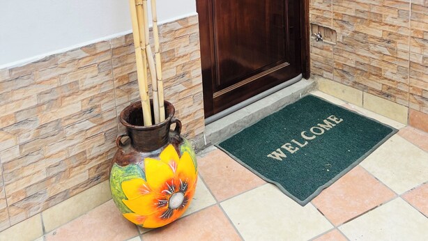 A wooden door with a metal handle, a welcome mat, and a decorative vase with bamboo sticks. - Cozy studio apartment in the center, steps away from the cable car 🚡 (La Paz)