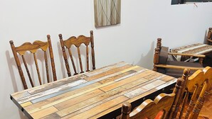 A dining area with a wooden table and chairs, a painting on the wall, and a window with blinds. - Cozy studio apartment in the center, steps away from the cable car 🚡 (La Paz)