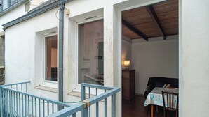 Ein Zimmer mit Holzboden, einem Esstisch mit Stühlen, einer Couch und einem kleinen Schrank.