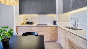 A modern kitchen with a marble countertop, wooden cabinets, a built-in stove, and a sink. - Modern Coast Concón- 2D w/ Wifi (Concón)