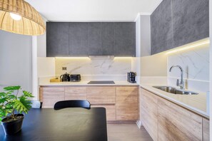 A modern kitchen with a marble countertop, wooden cabinets, a built-in stove, and a sink. - Modern Coast Concón- 2D w/ Wifi (Concón)