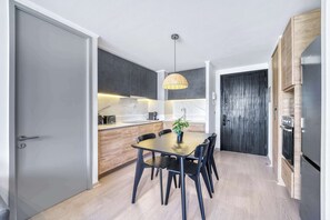 Eine moderne Küche mit Esstisch, Stühlen, einer Pendelleuchte und Einbau-Schränken.