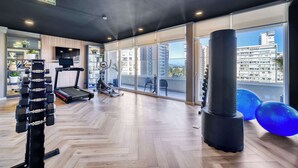 A gym with exercise equipment, a treadmill, and large windows with a city view. - Modern Coast Concón- 2D w/ Wifi (Concón)