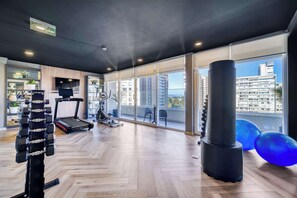 A gym with exercise equipment, a treadmill, and large windows with a city view. - Modern Coast Concón- 2D w/ Wifi (Concón)