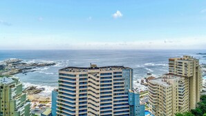 A high-rise hotel with multiple balconies overlooking a coastal area with rocky terrain and the ocean. - Vista Pacífico- 2D , Sea View and Wifi (Viña del Mar)