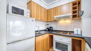 A compact kitchen with a refrigerator, stove, oven, microwave, and a coffee maker. - Vista Pacífico- 2D , Sea View and Wifi (Viña del Mar)