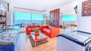 A spacious living area with a red sofa, a glass coffee table, and a view of the sea through large windows. - Vista Pacífico- 2D , Sea View and Wifi (Viña del Mar)