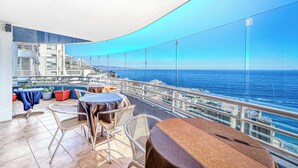 A balcony with tables and chairs, overlooking a coastal cityscape and the sea. - Vista Pacífico- 2D , Sea View and Wifi (Viña del Mar)