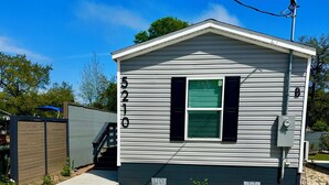 A single-story house with a garage, a small window with shutters, and a number '5210' on the side. - Welcome to vacation Home five minutes from the beach. 🏖️ (Pensacola)