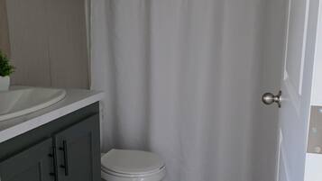 A bathroom with a toilet, a sink, a towel rack, and a shower curtain.