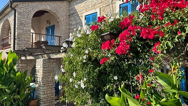 Un edificio in pietra con un balcone, una porta e una finestra con persiane blu.