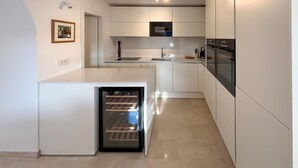 Una cucina compatta con elettrodomestici integrati, un piccolo frigorifero e un lavello.