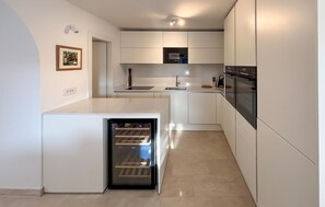 Eine kompakte Küche mit integrierten Geräten, einem kleinen Kühlschrank und einem Spülbecken.
