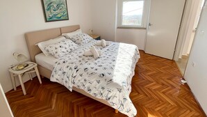 Una camera da letto con un letto, un comodino, un quadro, una finestra e una porta.