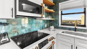 Een moderne keuken met een inbouwmagnetron, kookplaat en spoelbak.
