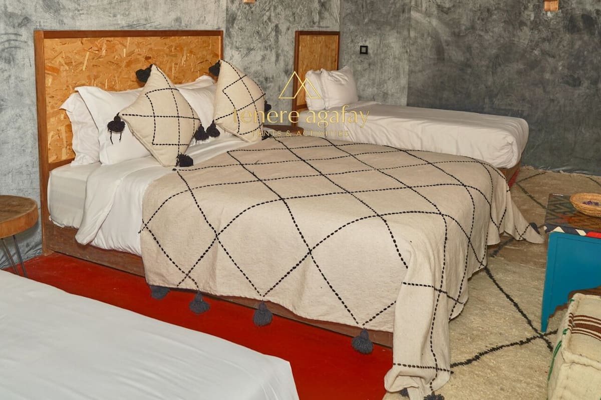 Una habitación con dos camas, cabeceros de madera y alfombra roja.