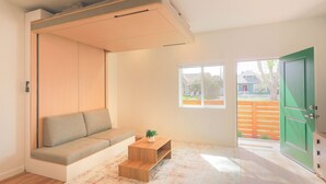 Ein Zimmer mit einer eingebauten Sitzbank, einem kleinen Holztisch mit einer Pflanze und einer grünen Tür.