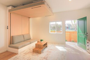 Ein Zimmer mit einer eingebauten Sitzbank, einem kleinen Holztisch mit einer Pflanze und einer grünen Tür.