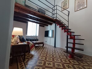A room with a loft bed, a desk with a lamp, a television, and a patterned floor. - Lovely vintage appartament Inalpi-Torino (Torino)
