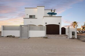 A modern two-story house with a gated entrance, a covered patio, and a garage.