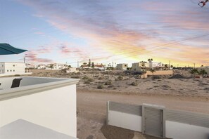 A desert landscape with buildings, a clear sky, and a sunset.