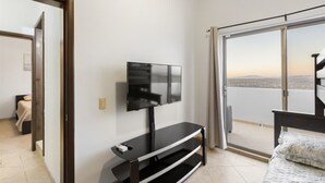 Una habitación con televisión sobre un mueble, cama y balcón con vistas.