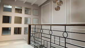 A staircase with a black metal railing, a polished white floor, and a series of mirrors on the wall. - Boutique N Laureles (Medellín)