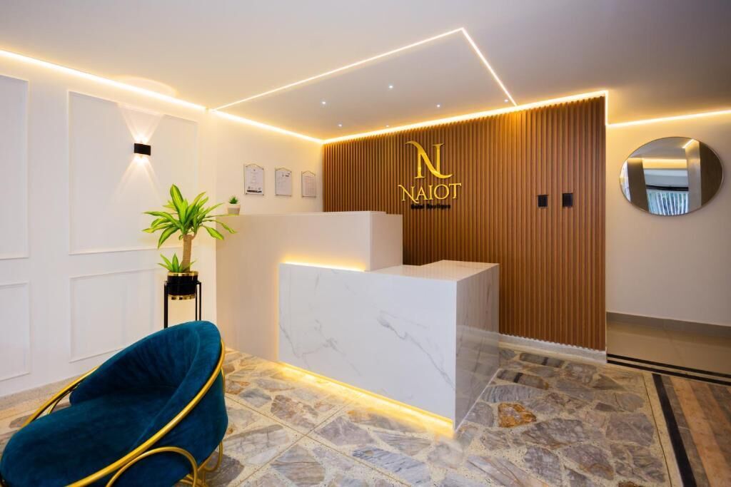 A reception area with a marble counter, a wooden panel wall, a round mirror, and a blue chair.