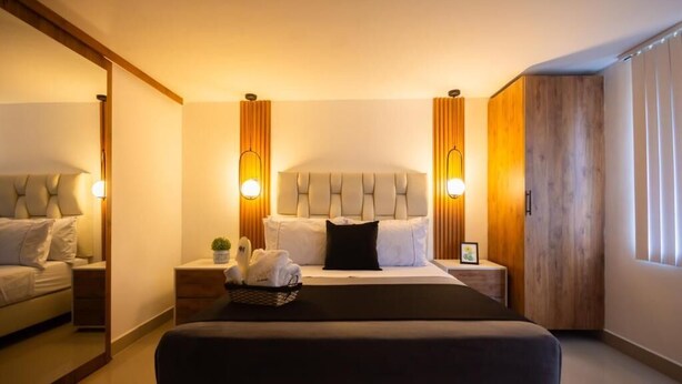 A modern bedroom with a large bed, bedside tables, a mirror, and a wardrobe. - Boutique N Laureles (Medellín)