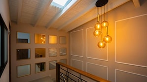 A staircase with a wooden handrail, a skylight, and wall-mounted spherical light fixtures. - Boutique N Laureles (Medellín)