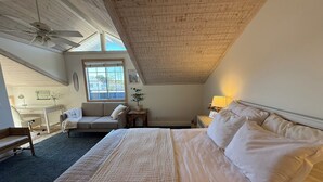 Camera da letto con un ampio letto, una scrivania, una sedia, una finestra e una ventola a soffitto.