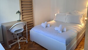 Una habitación de hotel ordenada con una cama, un escritorio y una silla.