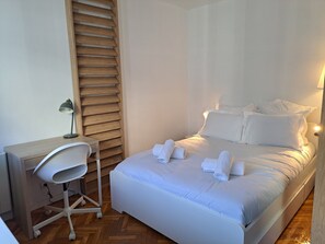 Ein ordentlich eingerichtetes Hotelzimmer mit einem Bett, einem Schreibtisch und einem Stuhl.