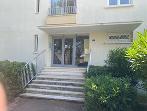 A two-story building with a front entrance, a balcony on the upper floor, and a set of concrete steps leading up to the door. - Apartment, pets welcome, AC - lake view (Balaruc-les-Bains)