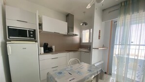 Eine kleine Küche mit Mikrowelle, Kühlschrank und einem Tisch mit Tischdecke.