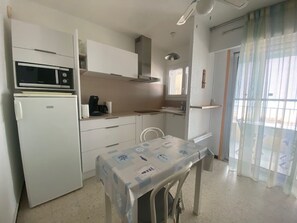A compact kitchen with a microwave, refrigerator, and a table with a tablecloth. - Apartment, pets welcome, AC - lake view (Balaruc-les-Bains)