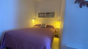 Ein Schlafzimmer mit Bett, Nachttischlampen, einem Regal mit Büchern und einer Wanddekoration in Form einer Sonne.