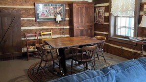 A rustic interior with a wooden dining table, chairs, a sofa, and a chandelier. - Blackberry Inn at Heritage Farm (Huntington)