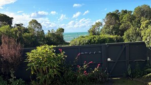 Ein Garten mit einem Weg zu einem Tor, umgeben von üppigem Grün und Blick aufs Meer.